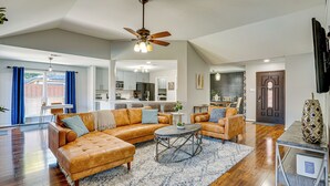 A spacious living room with a sectional sofa, a coffee table, and a ceiling fan. - Outdoor Oasis w/ Pool: Grand Prairie Family Home! (Grand Prairie)
