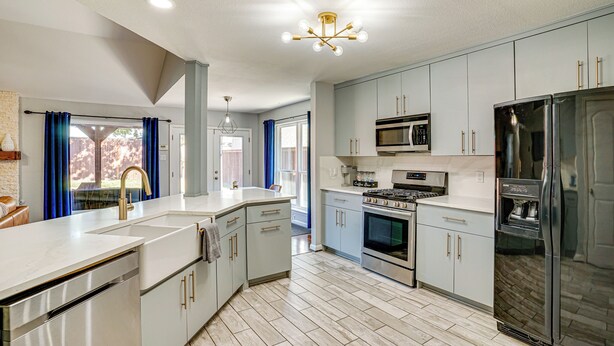 A modern kitchen with white cabinets, stainless steel appliances, and a large island with a sink. - Outdoor Oasis w/ Pool: Grand Prairie Family Home! (Grand Prairie)