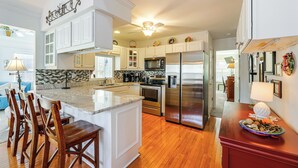 A modern kitchen with white cabinets, stainless steel appliances, and a wooden island with bar stools. - 8 Mi to Beach: Ocean Pines Home Near Marina & Golf (Berlin)