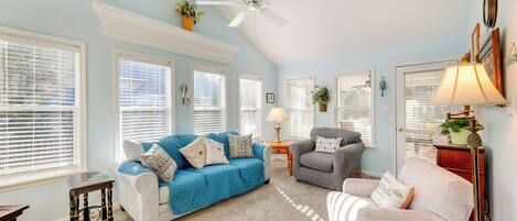 A living room with a blue and white color scheme, a ceiling fan, and a fireplace mantel.
