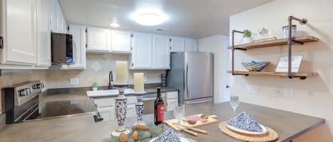 Uma cozinha moderna com armários brancos, eletrodomésticos de aço inoxidável e bancada de granito.