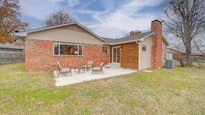 A two-story house with a brick exterior, a wooden front door, and a small patio with outdoor furniture. - 6 Mi to Dtwn: Dog-friendly Home w/ Yard in Tulsa (Tulsa)