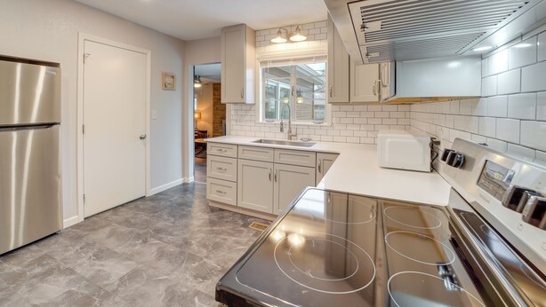 A modern kitchen with stainless steel appliances, white cabinetry, and a large window. - 6 Mi to Dtwn: Dog-friendly Home w/ Yard in Tulsa (Tulsa)