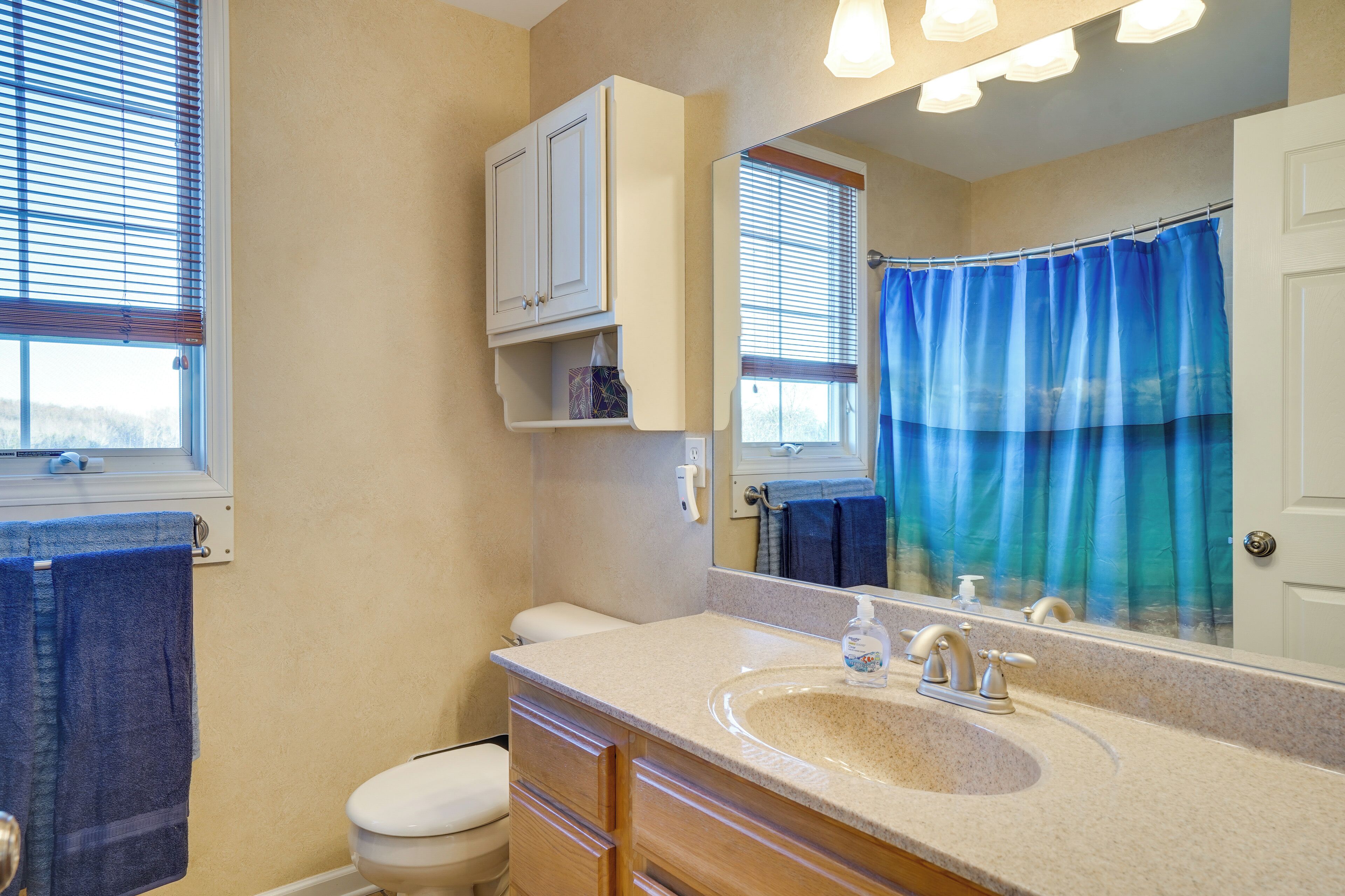 A bathroom with a toilet, sink, mirror, and a shower curtain.