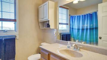 A bathroom with a toilet, sink, mirror, and a shower curtain.