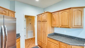 Una cocina con armarios de madera, encimera de granito y refrigerador de acero inoxidable.