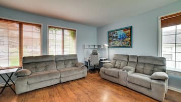 A living room with two grey sofas, a desk, and a computer chair.