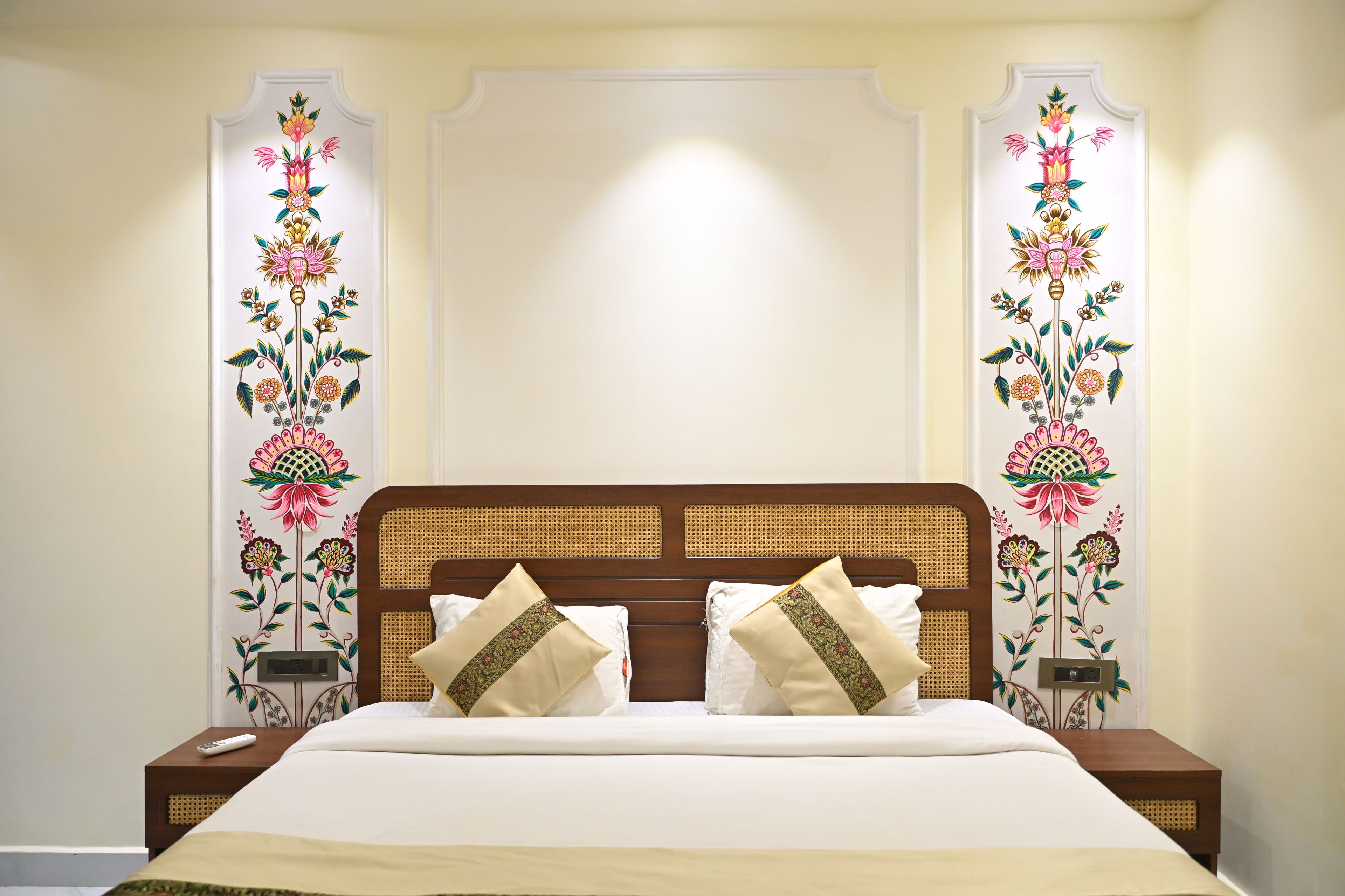 A hotel room with a bed, two nightstands, and decorative wall panels.
