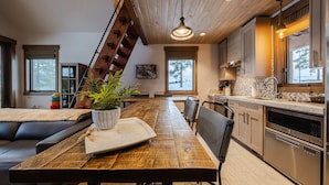 Une cuisine moderne dotée de meubles en bois, d’appareils électroménagers en acier inoxydable et d’un coin repas avec une table et des chaises en bois.