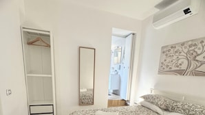 A bedroom with a large bed, a wardrobe, a mirror, and a bathroom visible through an open door. - House named Borghesia in the heart of the Sanità district of Naples (Napoli)