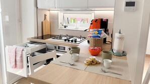 A modern kitchen with white cabinets, a gas stove, a microwave, and a small window. - House named Borghesia in the heart of the Sanità district of Naples (Napoli)