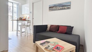 A modern living room with a grey sofa, a wooden coffee table with books, and a cityscape painting on the wall. - House named Borghesia in the heart of the Sanità district of Naples (Napoli)