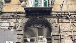 A building with a metal gate, a balcony with green shutters, and a sign for 'CIOCCOLATO Marie Galazzi NAPOLI'. - House named Borghesia in the heart of the Sanità district of Naples (Napoli)