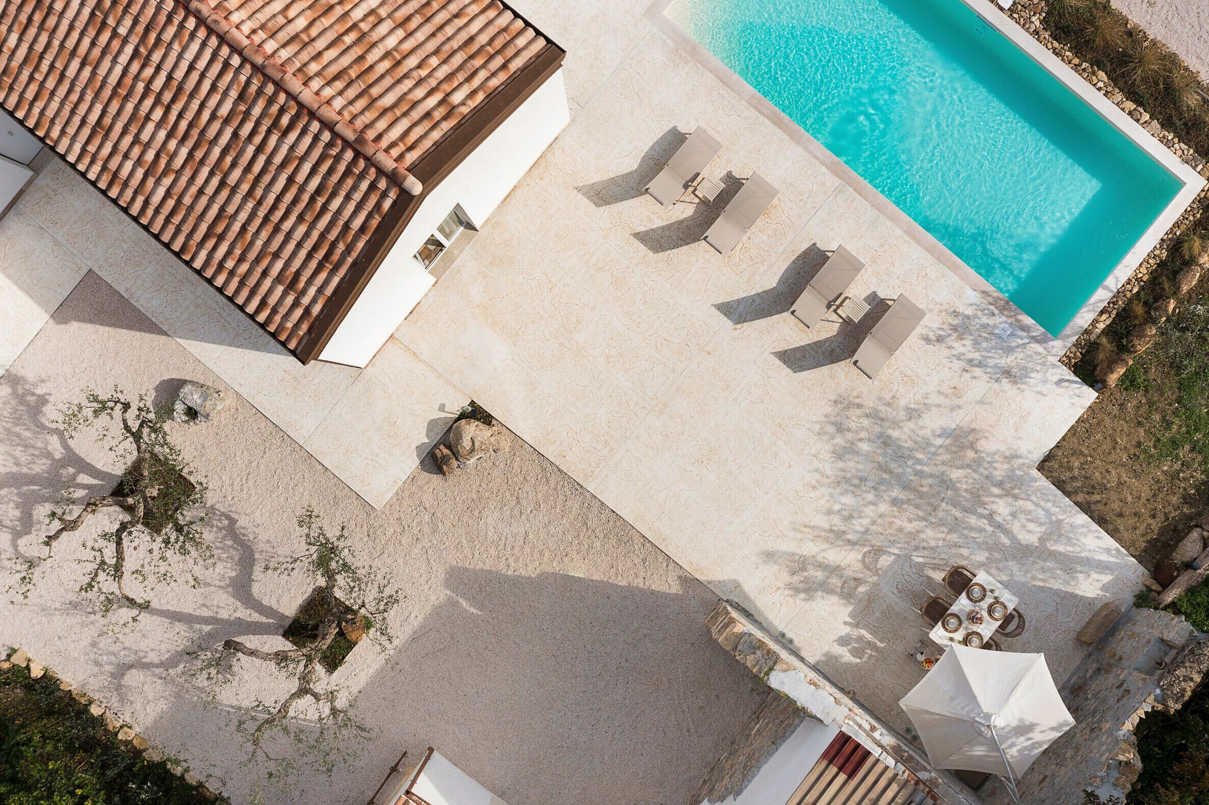 Vista aérea de uma área de piscina com espreguiçadeiras e uma mesa.