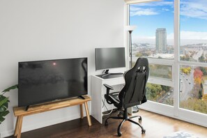 Work in comfort with a large flat-screen TV, desktop computer, and ergonomic office chair.