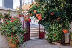 Stroll up the gated driveway to a Mediterranean-inspired entrance, surrounded by lush greenery and vibrant flowers.