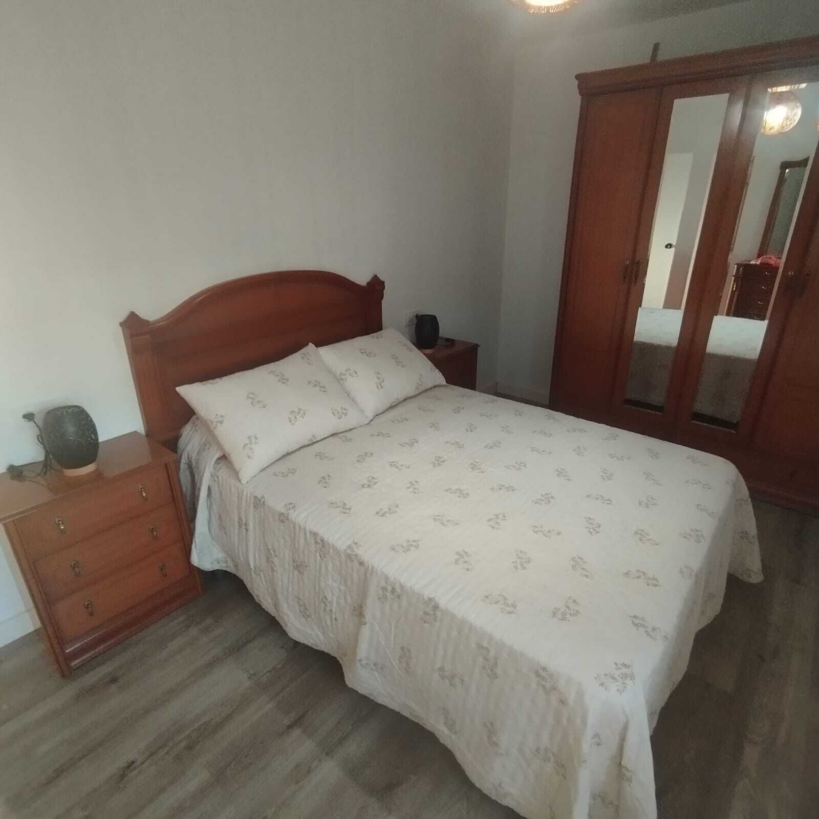 A bedroom with a wooden bed, a nightstand, a dresser, and a wardrobe.