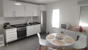 A modern kitchen with white cabinets, a stainless steel refrigerator, and a dining area with a round table and white chairs. - House pontevedra, enjoys tranquility 5 min from the beach and 3 min from downtown  (Pontevedra)