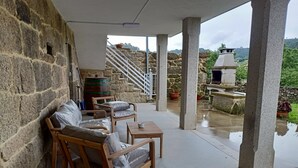 A covered outdoor seating area with stone walls, a wooden bench, and a view of a stone staircase and greenery. - House pontevedra, enjoys tranquility 5 min from the beach and 3 min from downtown  (Pontevedra)