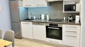 A modern kitchen with white cabinetry, a stainless steel refrigerator, a built-in microwave, a stove, and a dishwasher. - Charming, Fun, 3-Suite Apartment in Vibrant Budapest (Budapest)