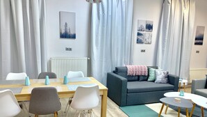A modern living room with a dining table, chairs, a sofa, and a coffee table. - Charming, Fun, 3-Suite Apartment in Vibrant Budapest (Budapest)