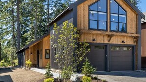 Une maison moderne à deux étages, dotée de grandes fenêtres, d’un garage et d’un jardin bien entretenu.