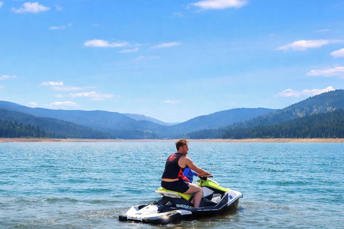A person on a jet ski on a lake with mountains in the background.