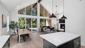 Une cuisine spacieuse dotée d’un grand îlot central, d’un plancher en bois et d’un coin repas avec une table et des chaises.