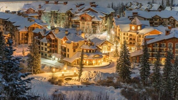 A snow-covered resort with multiple buildings, including a prominent lodge with a clock tower. - 1307b - King Standard Eagle Springs West Hotel Room (Solitude)