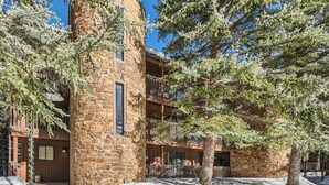 Un edificio de piedra con un balcón y un árbol en primer plano.