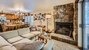 Una sala de estar acogedora con chimenea de piedra, un comedor con mobiliario de madera y una cocina con electrodomésticos modernos.
