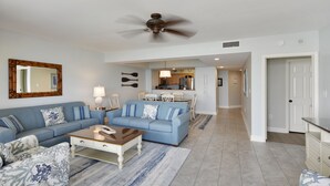 A spacious living room with a blue sofa set, a wooden coffee table, and a patterned rug.