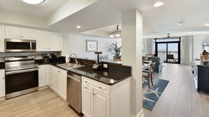 Una cocina moderna con armarios blancos, electrodomésticos de acero inoxidable y encimera de granito negro.