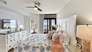 Un dormitorio con cama, televisor, ventilador de techo, cómoda y lámpara.