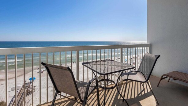 Un balcon avec une table et des chaises donnant sur une plage.