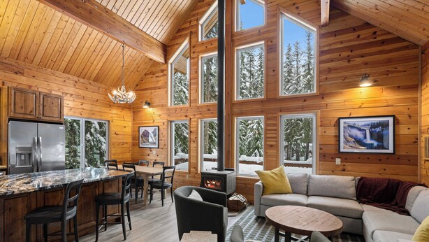 A log cabin interior with a kitchen, dining area, and living room.