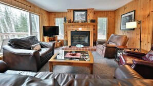 A cozy living room with leather sofas, a fireplace, and a television. - Lakefront Cabin with Dock, Kayaks, and Stunning Views on Quiet Teal Lake (Hayward)