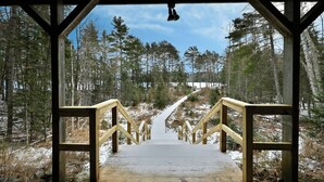 A wooden staircase leading into a forested area with a clear sky. - Lakefront Cabin with Dock, Kayaks, and Stunning Views on Quiet Teal Lake (Hayward)