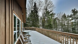 A wooden deck with a table and chairs, overlooking a forested area. - Lakefront Cabin with Dock, Kayaks, and Stunning Views on Quiet Teal Lake (Hayward)