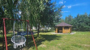 A playground with a swing set and a small wooden structure.