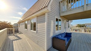 Una terraza de madera con un sofá integrado y un pequeño balcón.