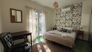 A bedroom with a bed, a desk, a chair, a mirror, and a window with curtains. - Candau Villa, a green haven with a wooded garden and a pool, 5min from Avignon (Les Angles)