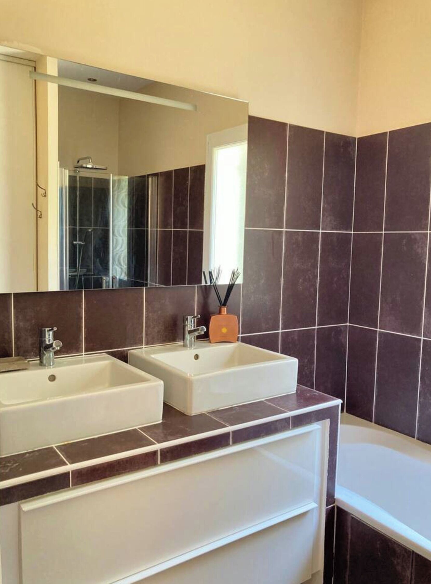A bathroom with two sinks, a mirror, and a shower.
