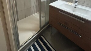 A modern bathroom with a glass shower enclosure, a white sink with a mirror above it, and a wooden vanity. - Village house Val cenis (Val-Cenis)