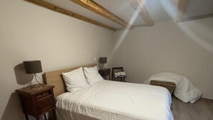 A bedroom with a wooden ceiling, a bed with white bedding, a nightstand with a lamp, and a small table with a lamp. - Village house Val cenis (Val-Cenis)