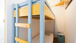 A bunk bed with a ladder, a bedside table, and a lamp.