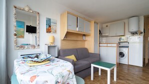 A compact living space with a dining table, sofa, and kitchenette.