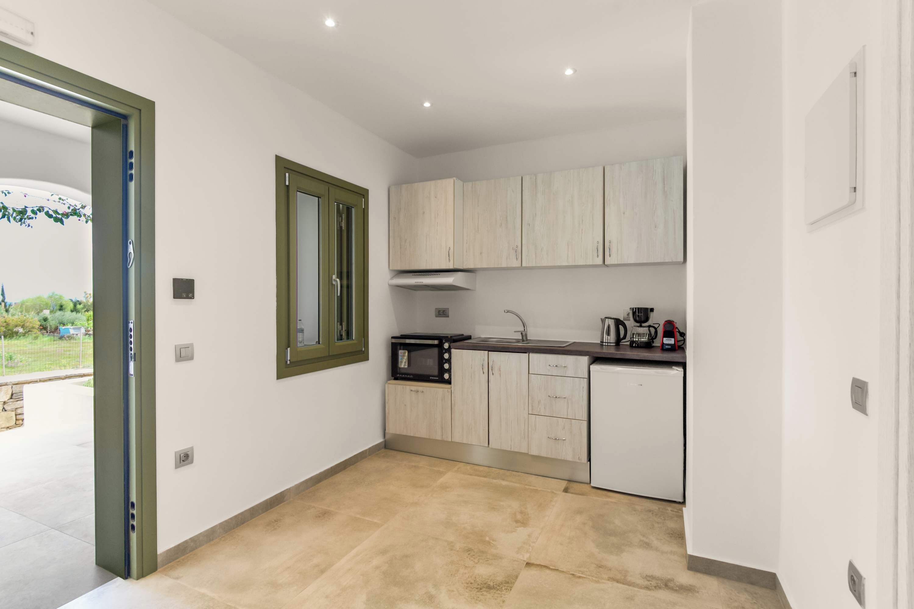 A modern kitchen with light wood cabinets, a built-in microwave, and a coffee maker.