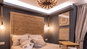 A bedroom with a large bed, a wooden headboard, a chandelier, and artwork on the walls.