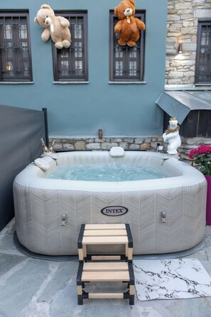 A hot tub with a wooden bench in front, surrounded by stone walls and windows. - Rock Dandy La Maison De L’Ours | Top Fireplace Retreat (Amyntaio)
